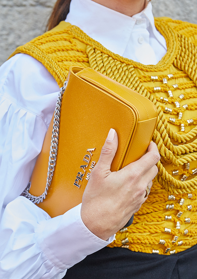 MILAN, ITALY - SEPTEMBER 24, 2021: Woman with yellow leather Prada bag and white shirt before Prada fashion show, Milan Fashion Week street style